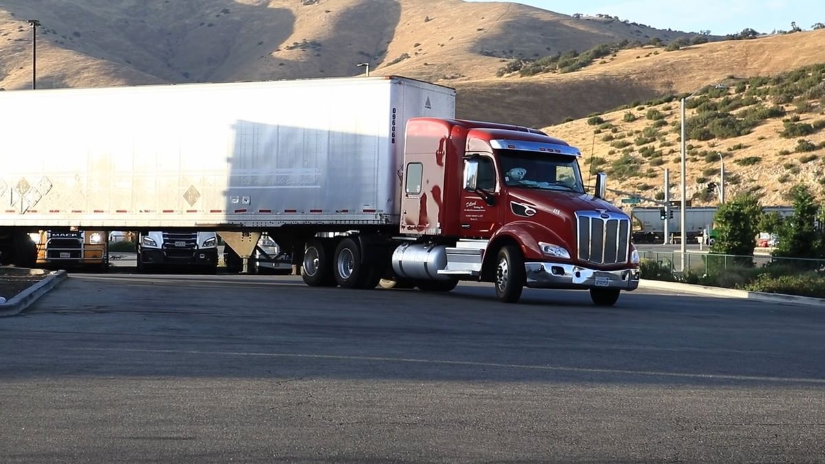 A red semi truck driving down a mountain highway
